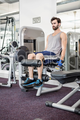 Focused man using weights machine for legs