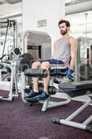 Focused man using weights machine for legs