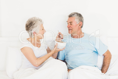 Happy senior woman feeding her husband