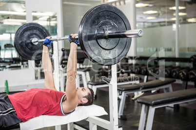 Muscular man lifting barbell on bench