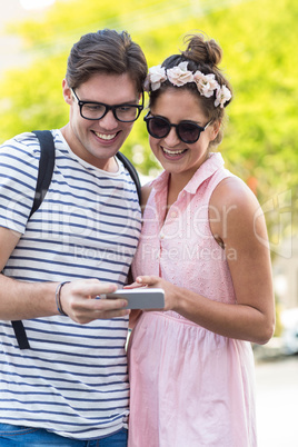 Hip couple looking at smartphone and laughing