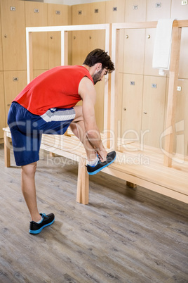 Man tying shoelace in locker room
