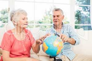 Smiling senior couple looking at globe