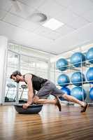 Serious man doing exercise with bosu ball