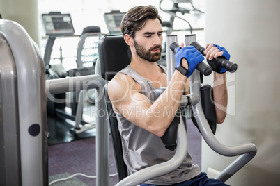 Focused man using weights machine for arms