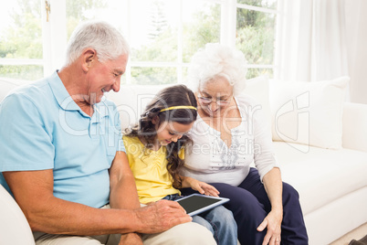 Grandparents using tablet with their granddaughter