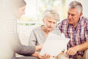 Smiling businesswoman showing documents to senior couple