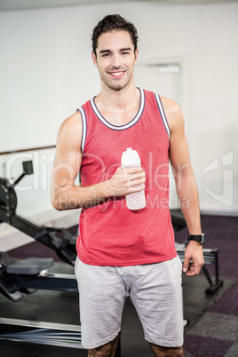 Smiling man standing and holding bottle of water