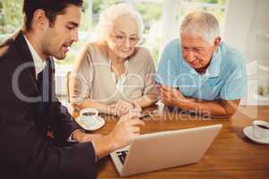 Businessman showing laptop to senior couple