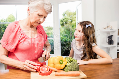 Grandmother and granddaughter slicing vegetables