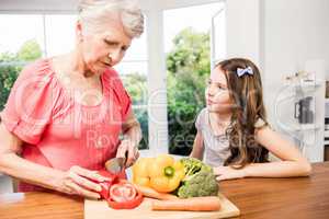 Grandmother and granddaughter slicing vegetables