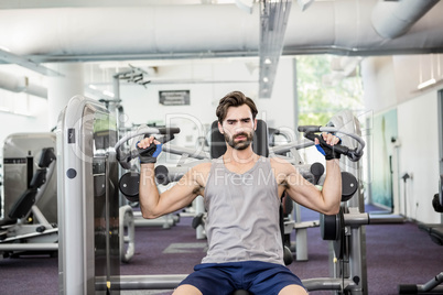 Focused man using weights machine for arms