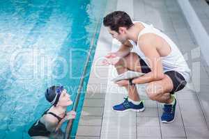 Fit trainer talking to swimmer