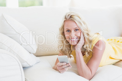 Happy woman using smartphone on the sofa