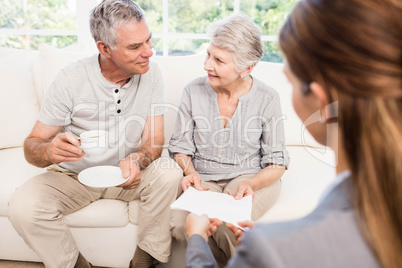 Businesswoman showing documents to senior couple