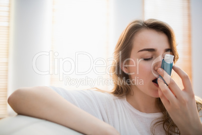 Woman using her inhaler on couch