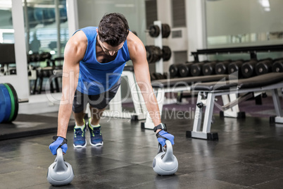 handsome man doing push ups with kettlebells