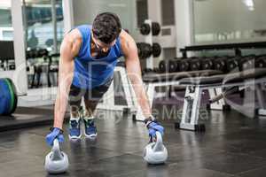 handsome man doing push ups with kettlebells