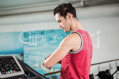 Serious man on treadmill looking at smart watch
