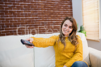 Smiling woman holding remote control on couch