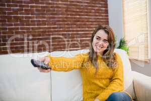 Smiling woman holding remote control on couch