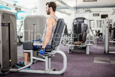 Focused man using weights machine for legs