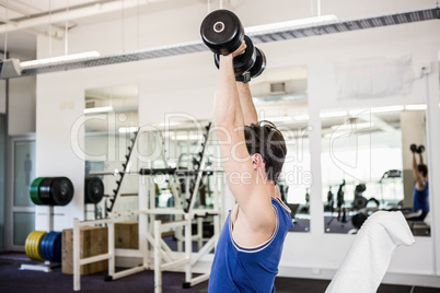 Muscular man lifting dumbbells on bench