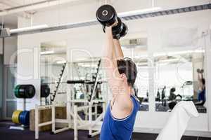 Muscular man lifting dumbbells on bench