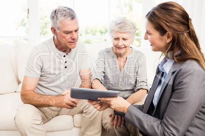 Businesswoman showing tablet to senior couple