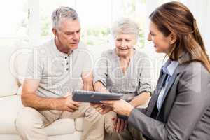 Businesswoman showing tablet to senior couple