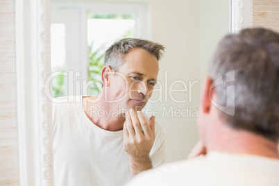 Handsome man looking at himself in the mirror