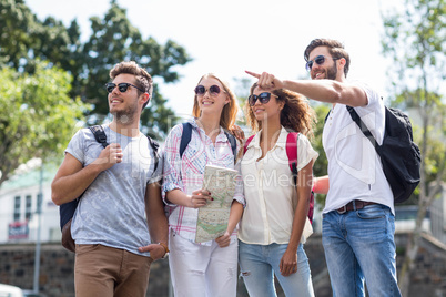 Hip friends holding map and pointing