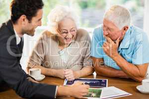 Businessman showing sheets to senior couple