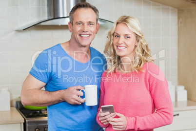 Cute couple having coffee and looking at smartphone