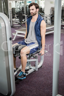 Focused man using weights machine for legs