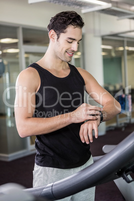 Smiling man on treadmill using smart watch