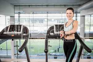 Smiling woman on treadmill using smart watch