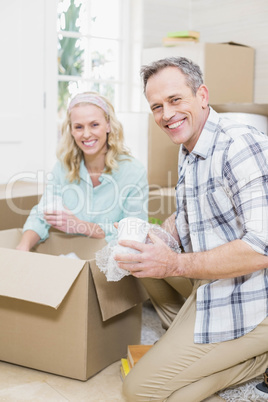 Smiling couple packing mug in a box