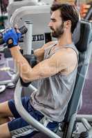 Focused man using weights machine for arms