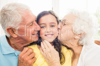 Grandparents kissing their granddaughter