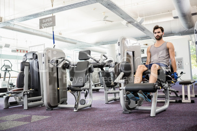 Focused man using weights machine for legs