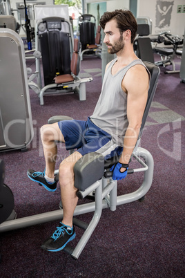 Focused man using weights machine for legs