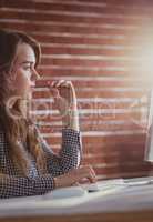 Thoughtful hipster businesswoman watching computer