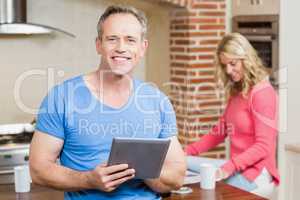 Husband using tablet while wife having breakfast