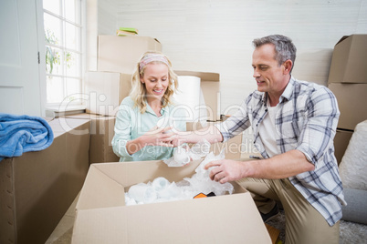 Smiling couple packing mug in a box