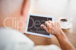 Elderly man using tablet and drinking coffee