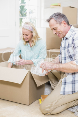 Smiling couple packing mug in a box