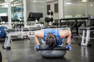 Muscular man doing push up with bosu ball