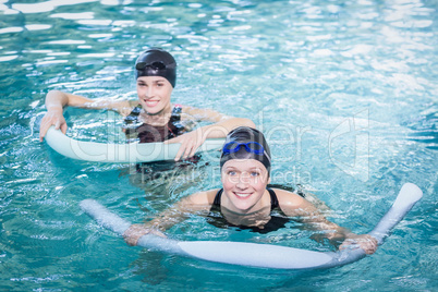 Smiling women in the pool with foam rollers