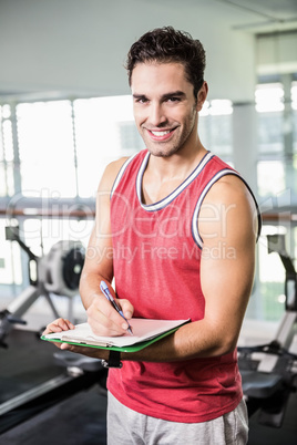Smiling man writing on clipboard